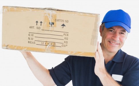 Portrait of happy delivery man carrying package against white backgeound